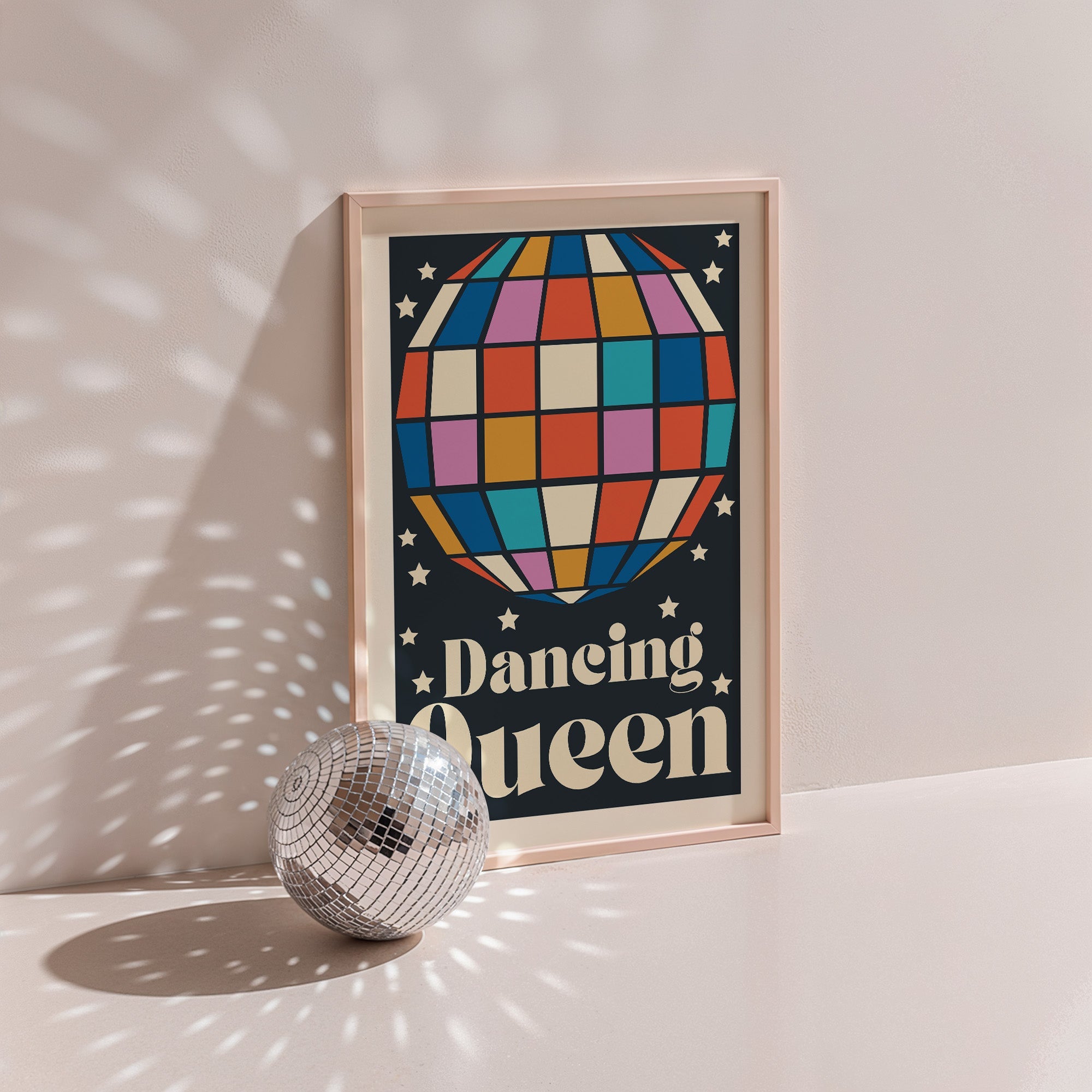 Dancing Queen poster in wood frame beside a disco ball, navy background with a multicoloured disco ball