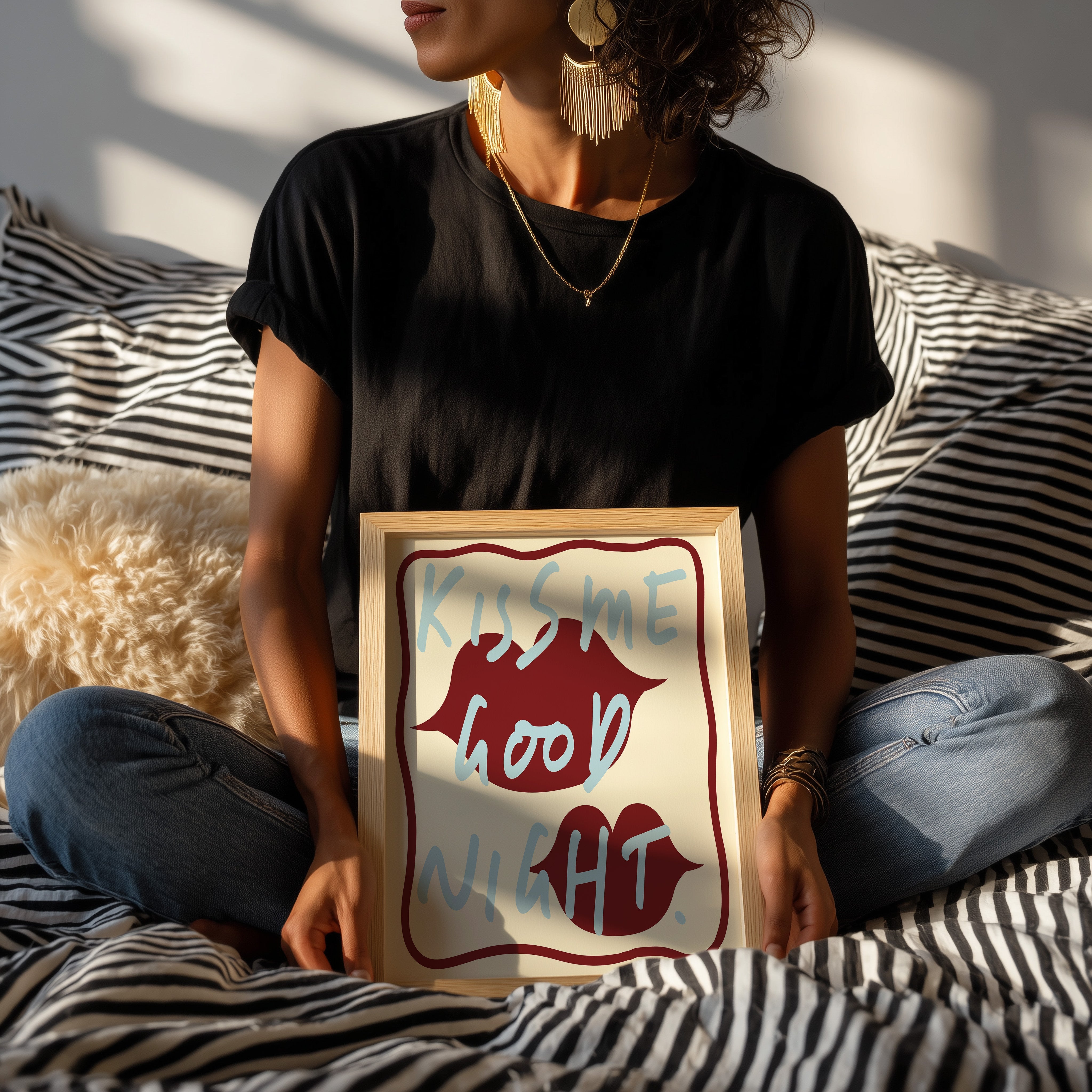 Illustrated print in wood frame held by a person sitting on a striped sofa