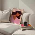 Framed artwork of a woman's face on a sofa with books and a mug.