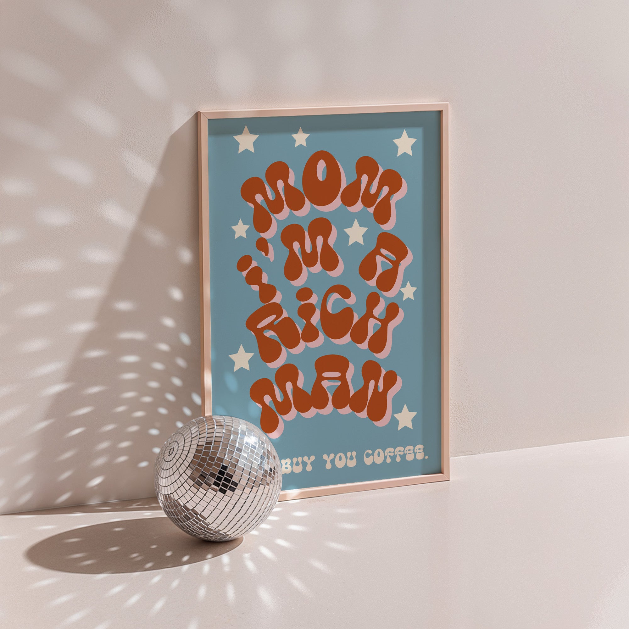 Mom I'm A Rich Man poster in wood frame beside a disco ball, orange bubble lettering with cream stars on blue