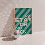 Do I Stay or Do I Go poster in wood frame beside a disco ball, bold cream lettering on candy stripes