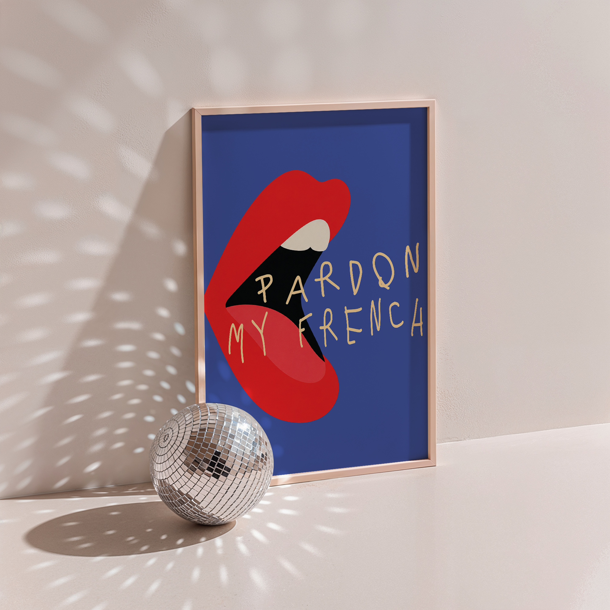 Pardon My French poster in wood frame beside a disco ball, red lips with lettering on blue